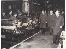 Zespół partyjno-rządowy w trakcie zwiedzania hali montażowej, po lewej stronie silniki w końcowej fazie produkcji